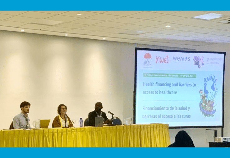 Three panelist sitting behind a table with a large presentation screen next to them