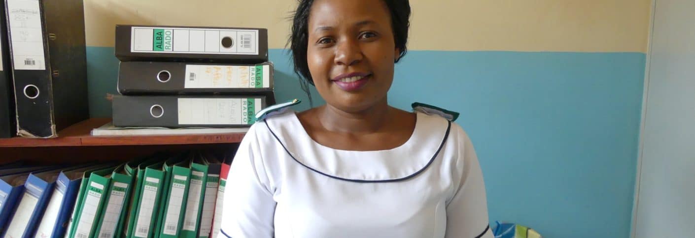 Nurse standing in an office, smiling at the camera