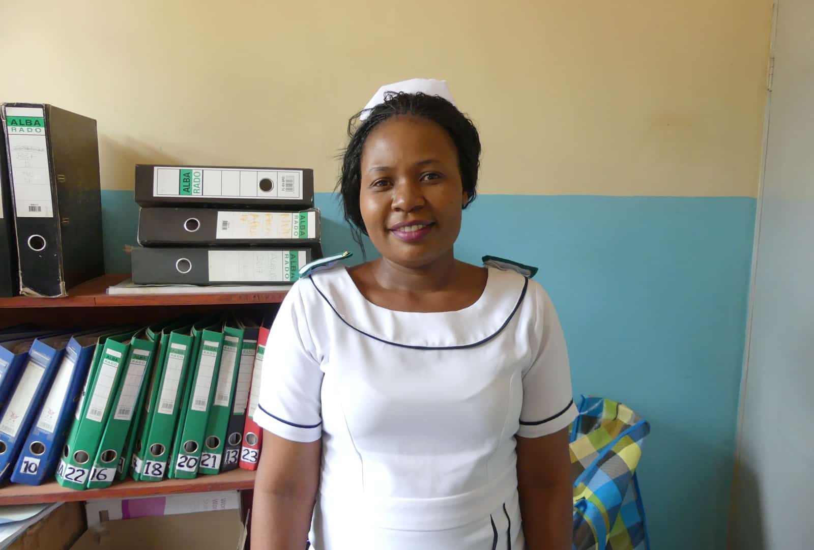 Nurse standing in an office, smiling at the camera